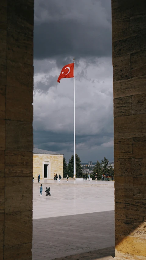 an ottoman courtyard under dark clouds is seen through a brick wall