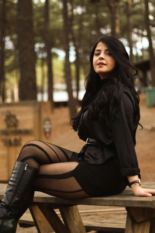 a pretty woman wearing all black sitting on a bench