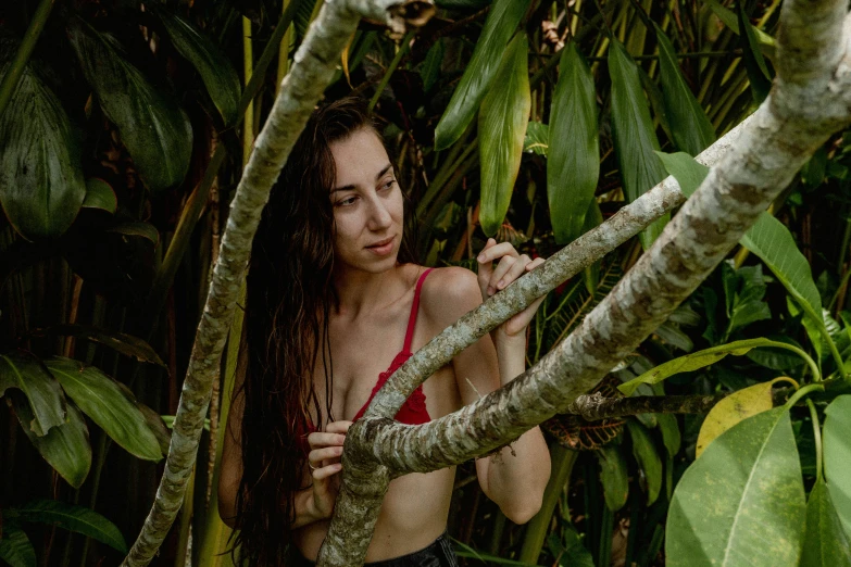 a young woman in a bikini with long hair, stands in a forest