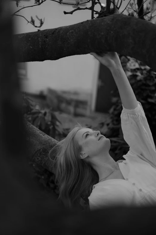 a woman is lying down on a tree nch