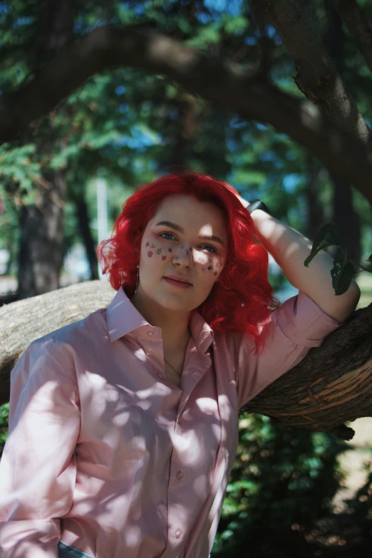 a woman with red hair standing near trees