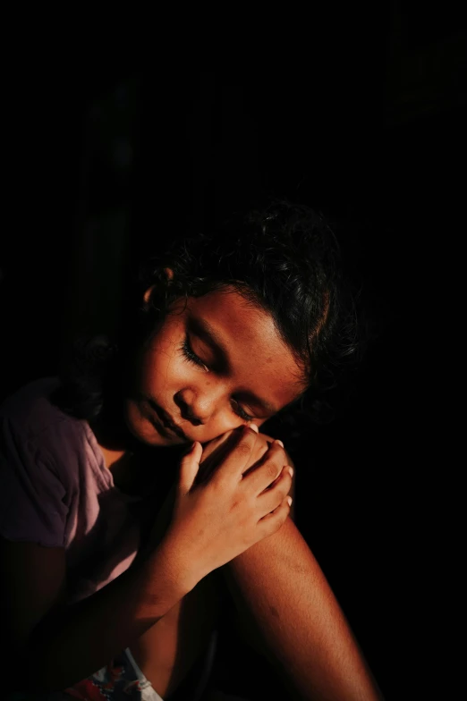 little girl is praying with her hands on the other side of her face