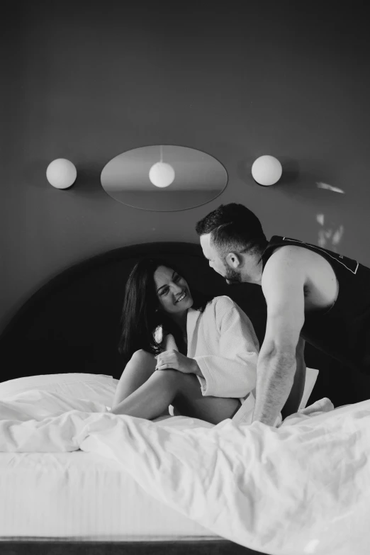 black and white pograph of young couple sitting on bed