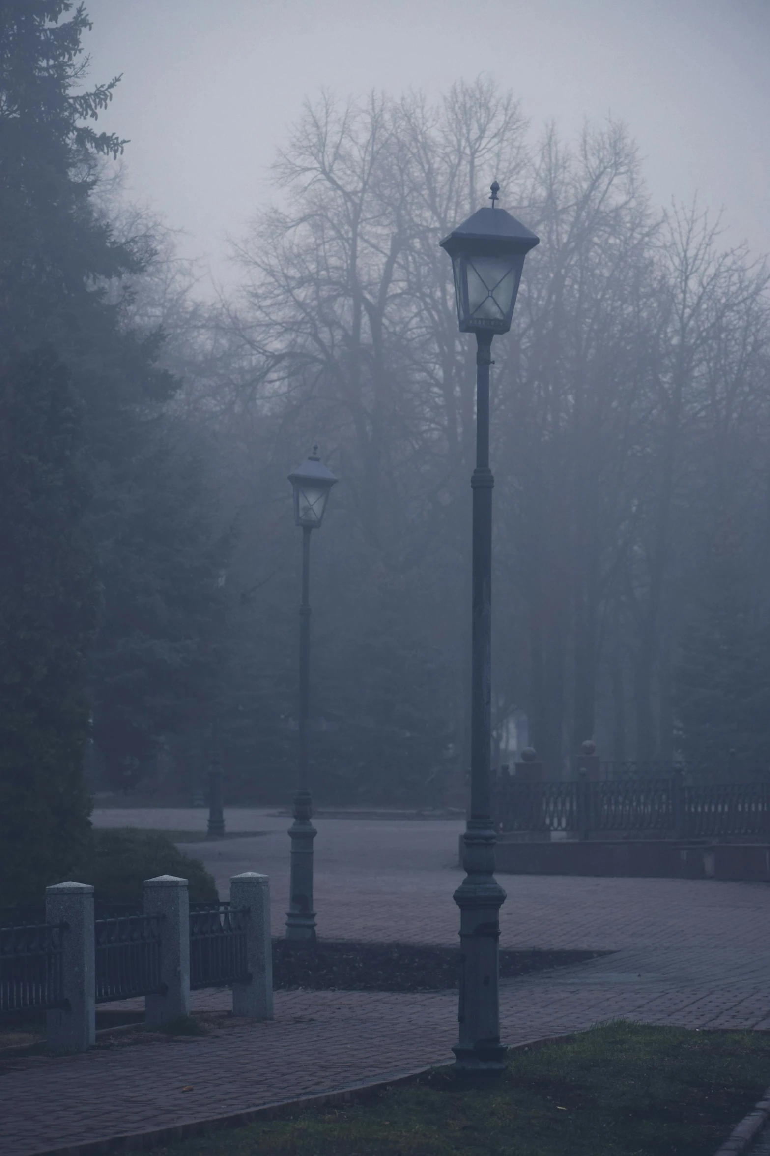 a lantern post on a paved street with trees in the background