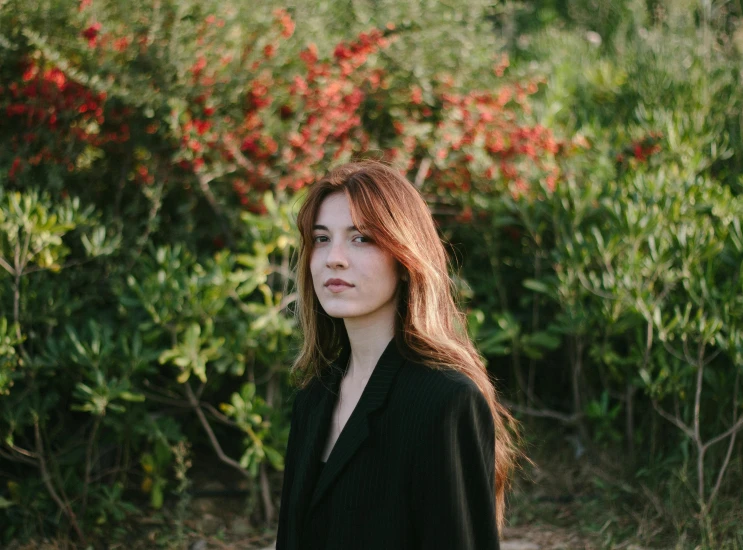 a young woman with red hair standing outside in the sun