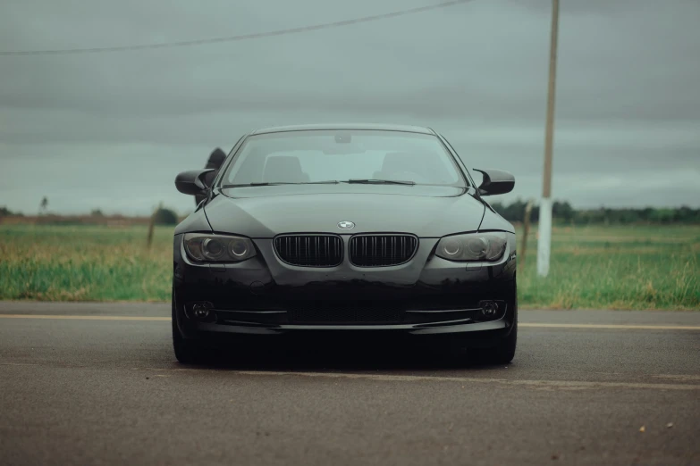 a bmw parked on the side of the road near grass