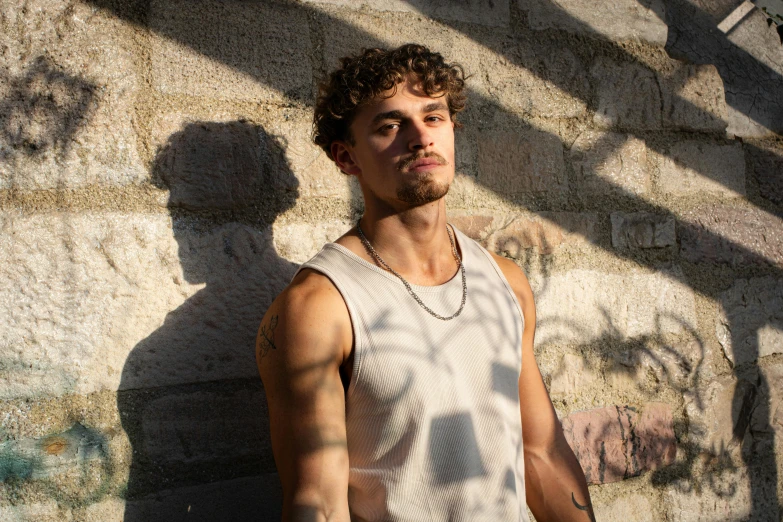 the man is standing near a wall wearing a chain