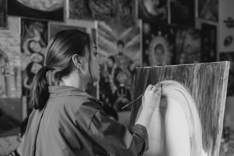 a woman holds a paintbrush to a white board