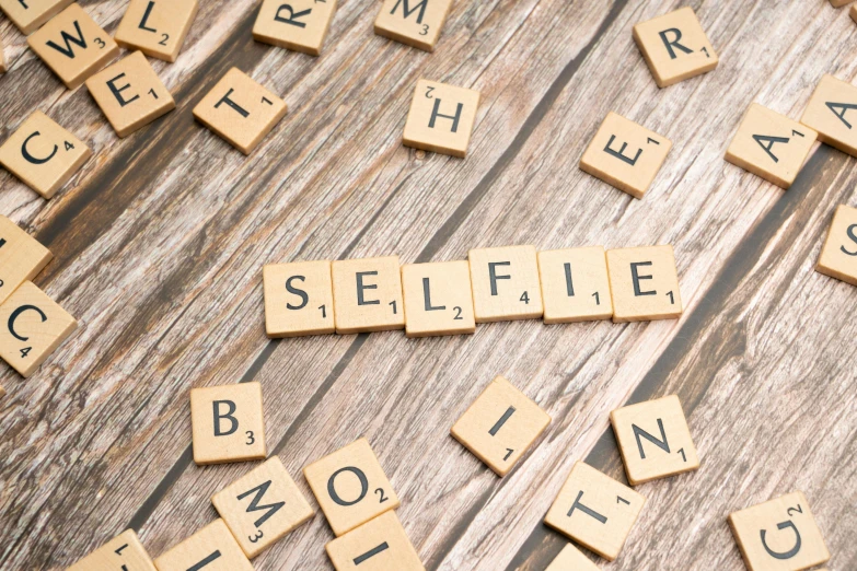 scrabbled letters that spell out selfie on a wooden floor