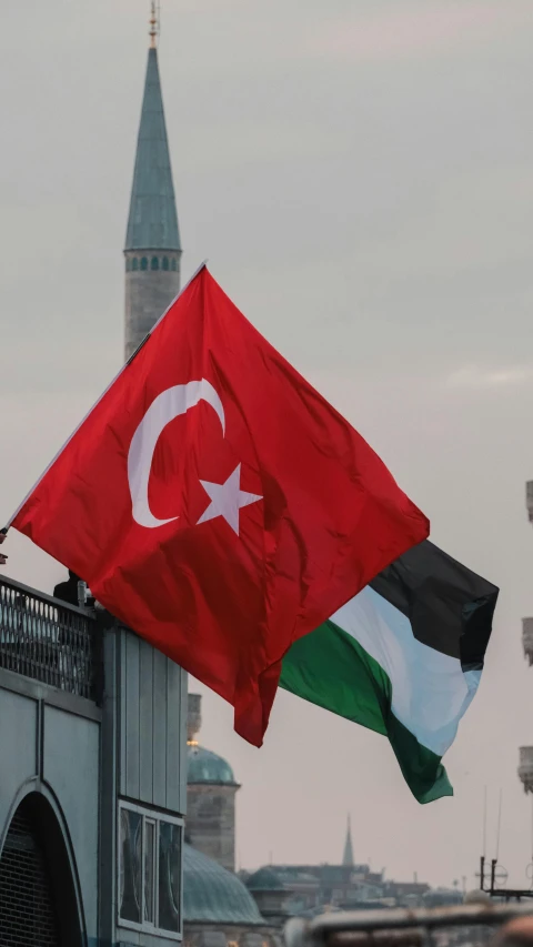 two flags are flying over a building with a steeple