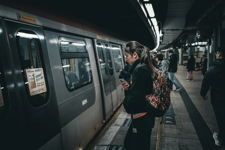 a lady in a black top is waiting for a subway train