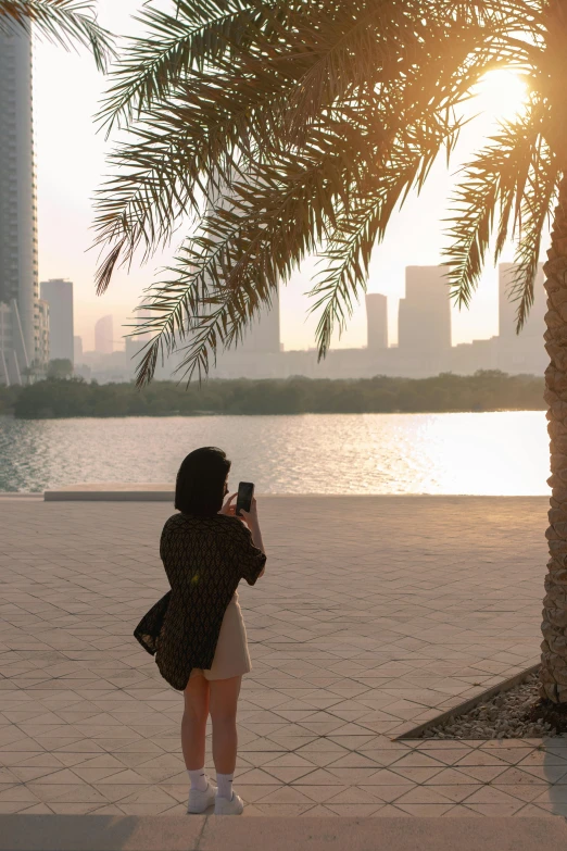 woman takes po of palm tree from the sidewalk