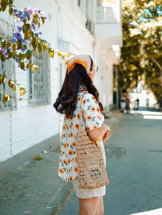 an asian woman walking down the sidewalk with a bag on her head