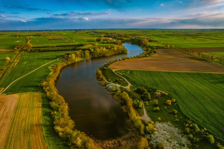an aerial view of a river flowing between two green fields