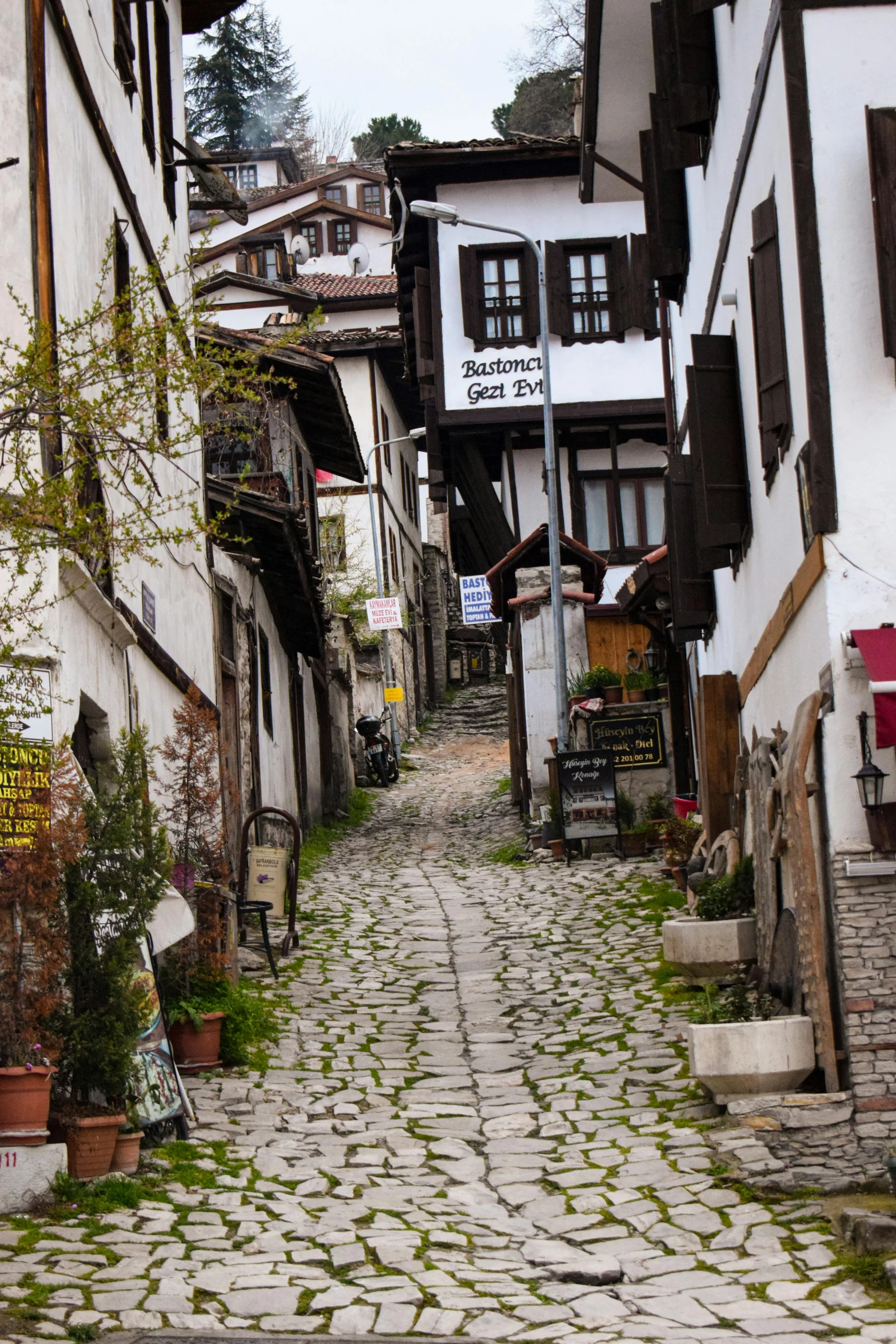 a narrow stone street is lined with white brick buildings