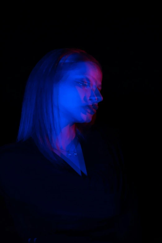 woman in dark with blue and pink light coming through