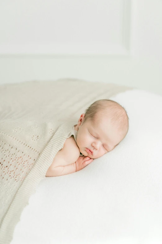 newborn baby sleeping peacefully on a white blanket