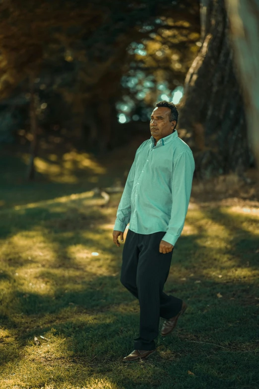 a man is standing and smiling outside in the grass