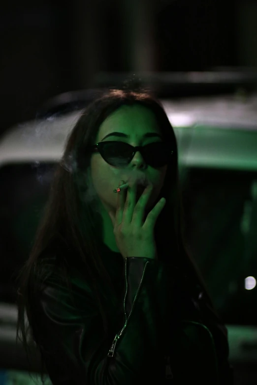 a woman smokes with her hands as she walks past a car