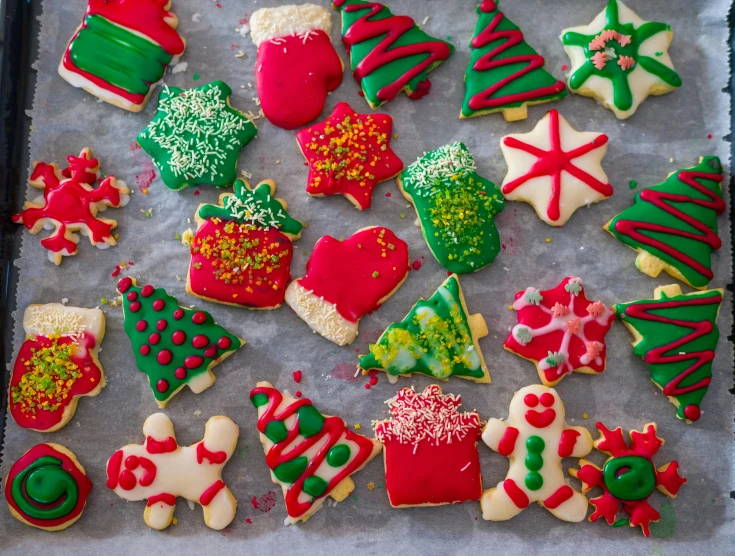 many decorated christmas cookies are on the baking sheet