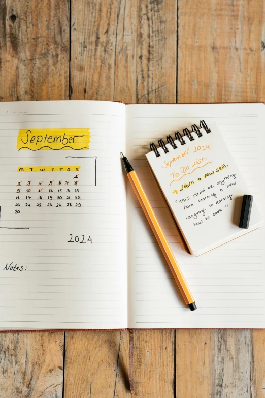 a calendar with a notepad and a pencil on a wooden table