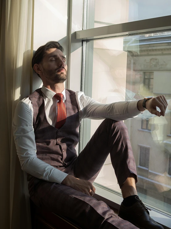 a man in suit sitting in a window sill