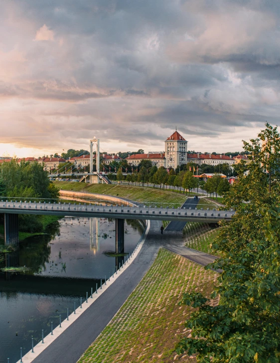 a river near trees with a bridge in the background