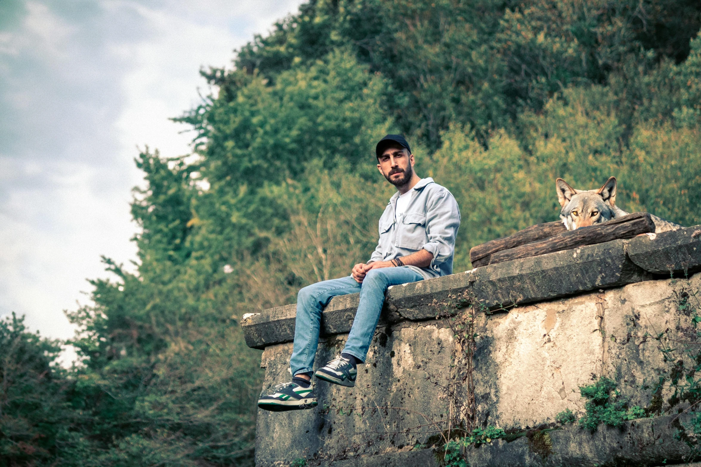 a man sits on a stone wall with his legs crossed