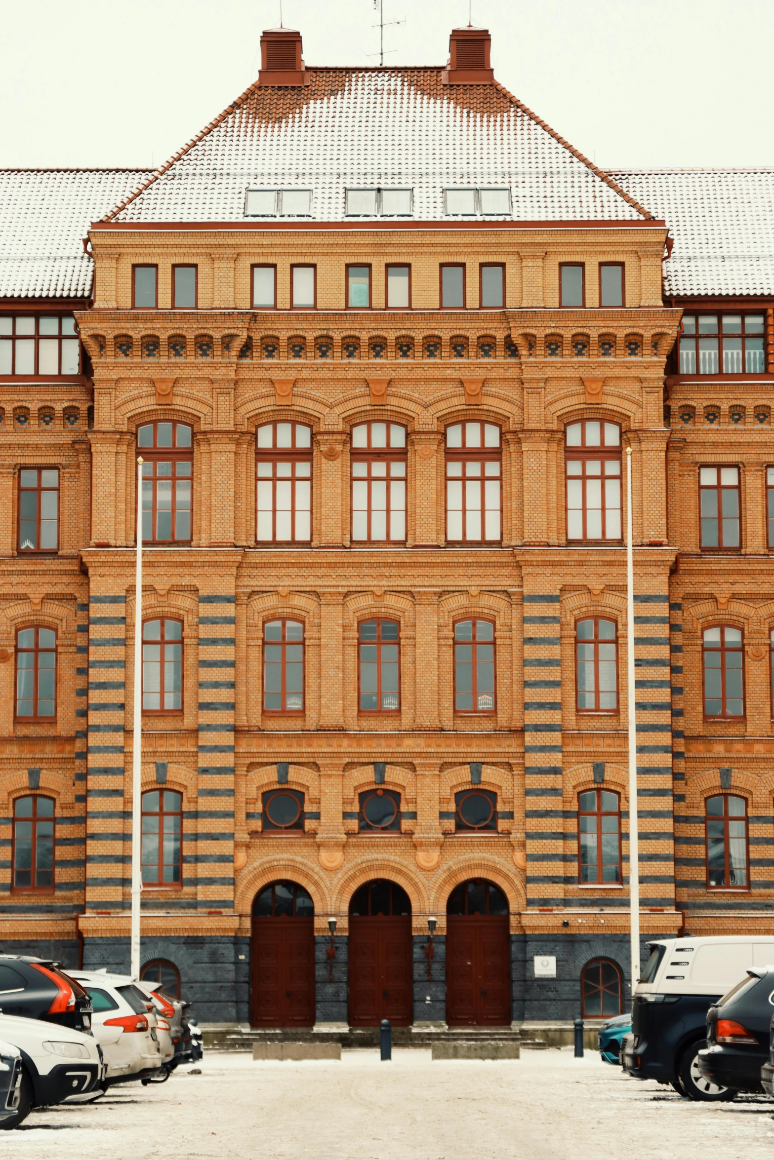 a very big and pretty big building by a lot of parked cars