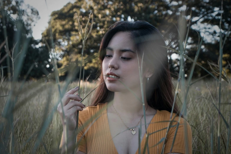 a girl is holding a cigarette in a field