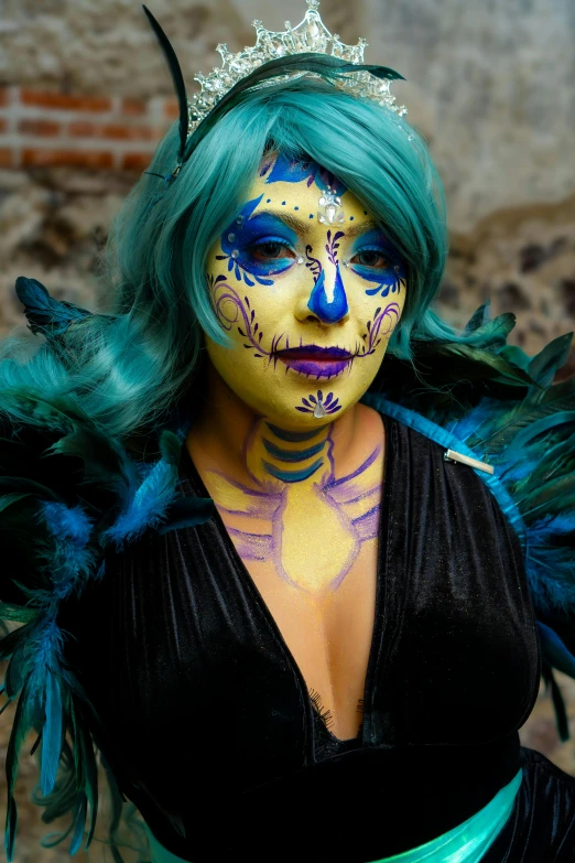 a woman in green and yellow makeup with feathers on her head