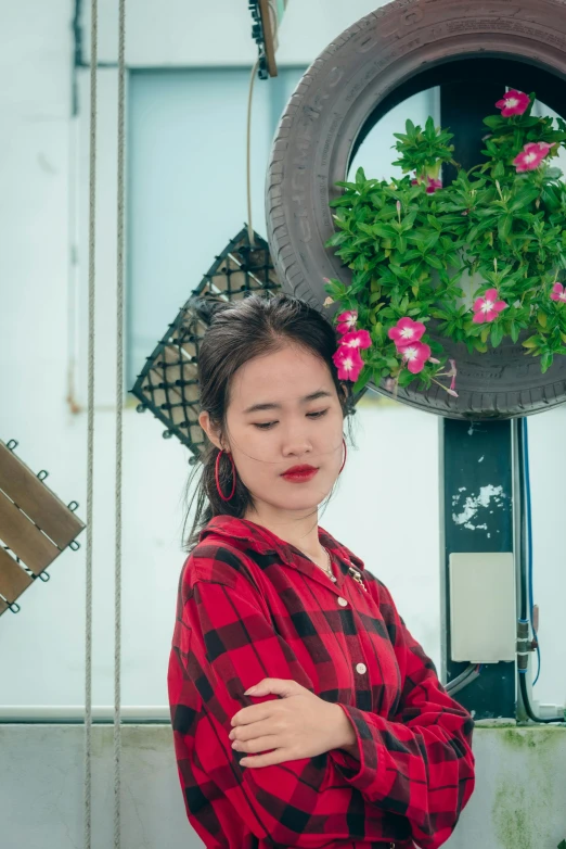 a woman stands beside a flower pot and her hands on her stomach