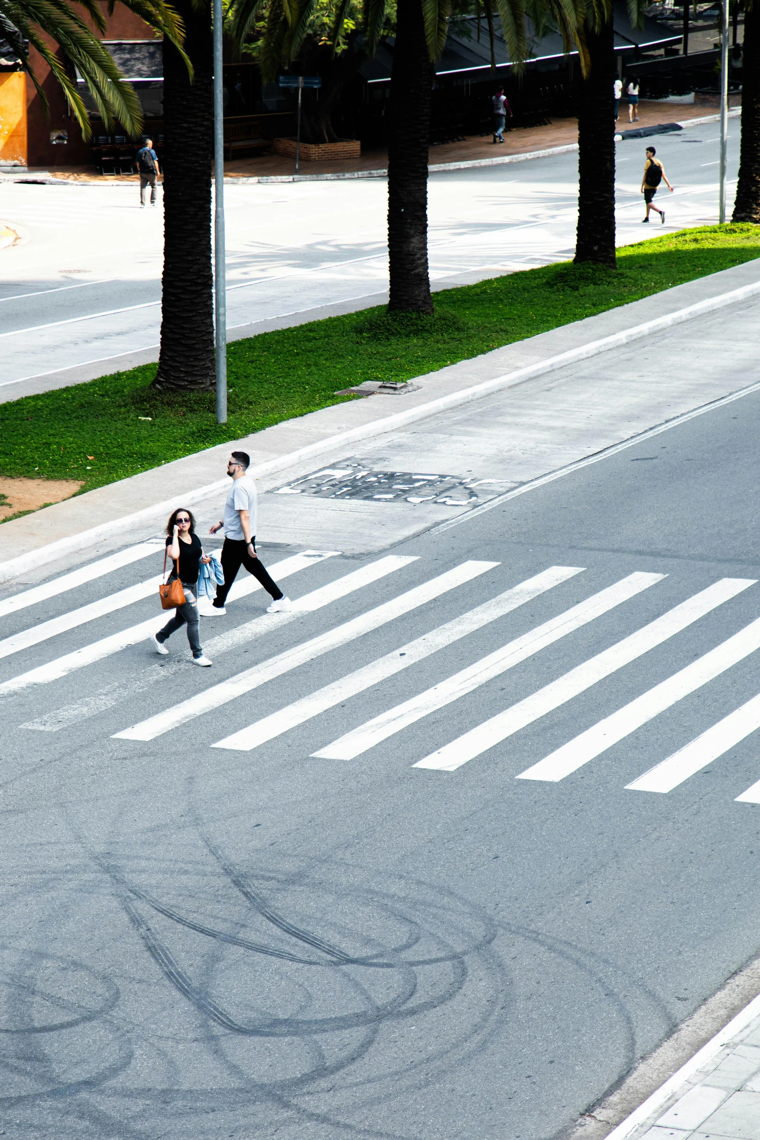 two girls crossing a city street in front of parked cars