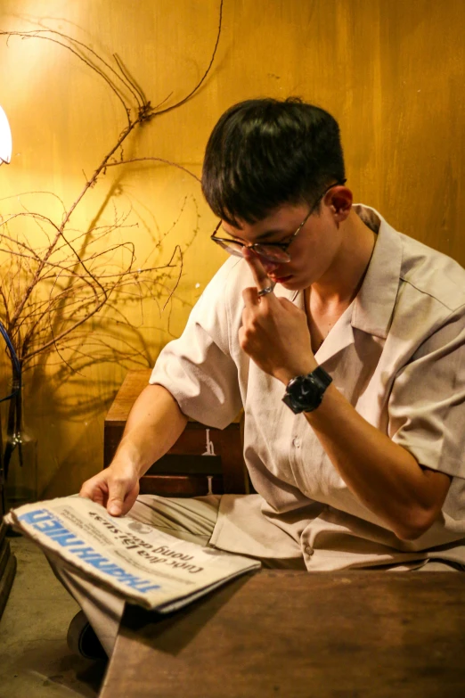 a man looking at his newspaper while sitting at a table