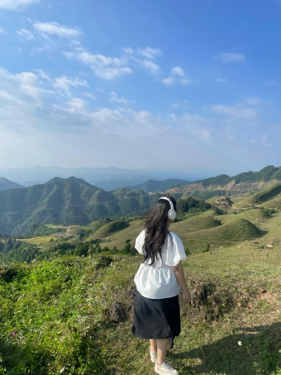 a girl walking down a hill next to some hills