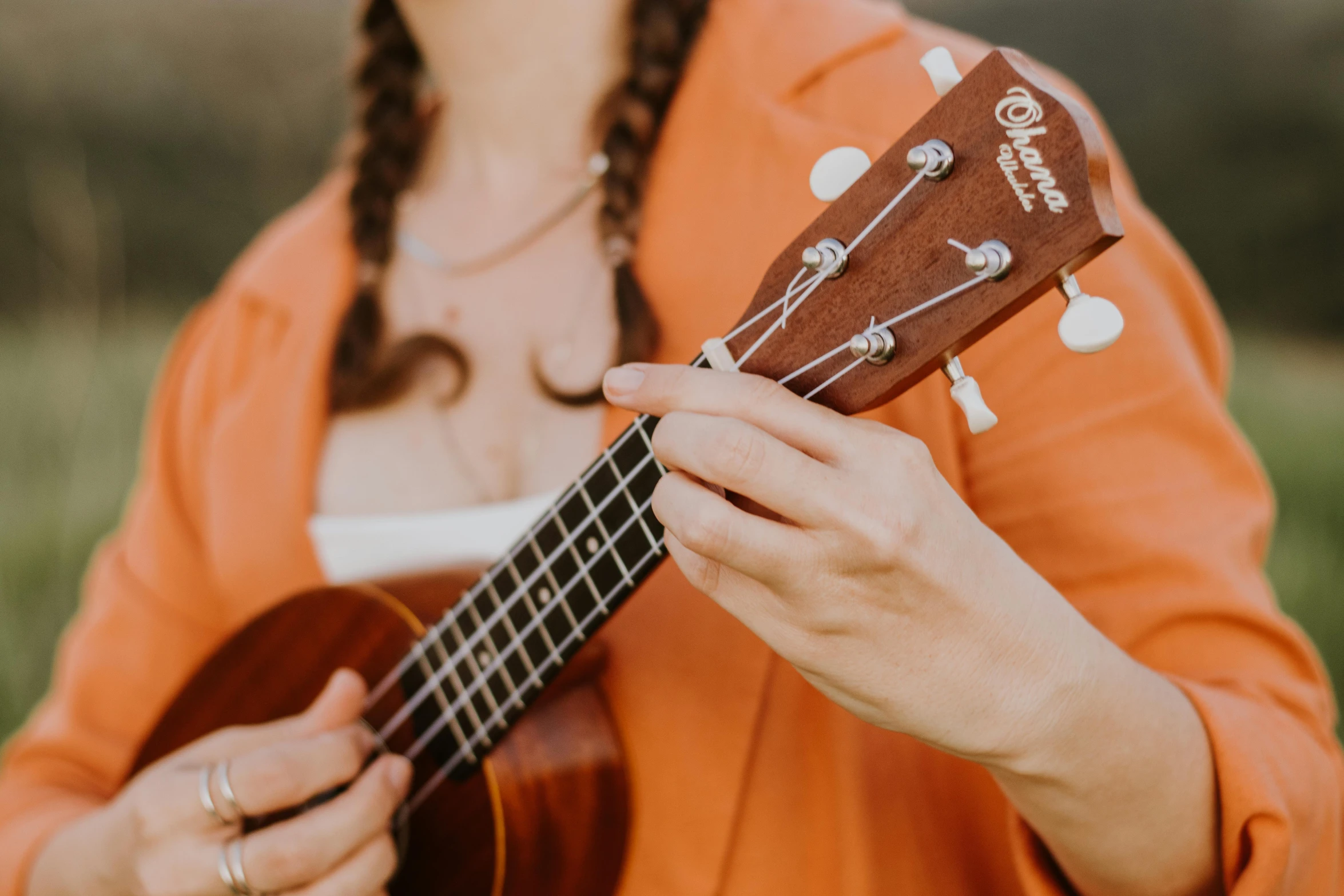 a woman holding an ukulele with her left hand and the other holding it with both fingers