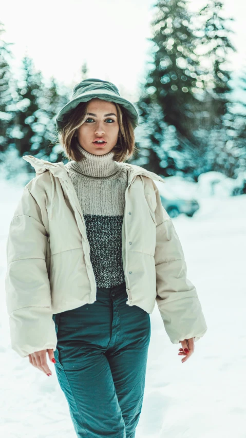 woman wearing a winter coat and hat walking through the snow