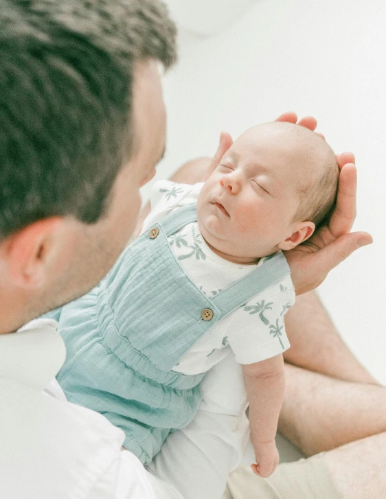 a man holding a baby while he puts his hand on the head