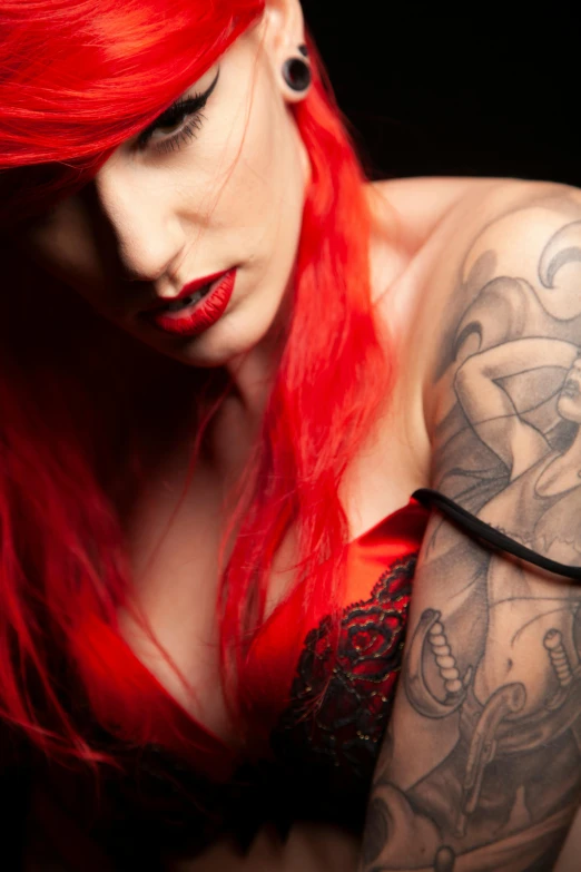 a woman with red hair has tattoos on her arm