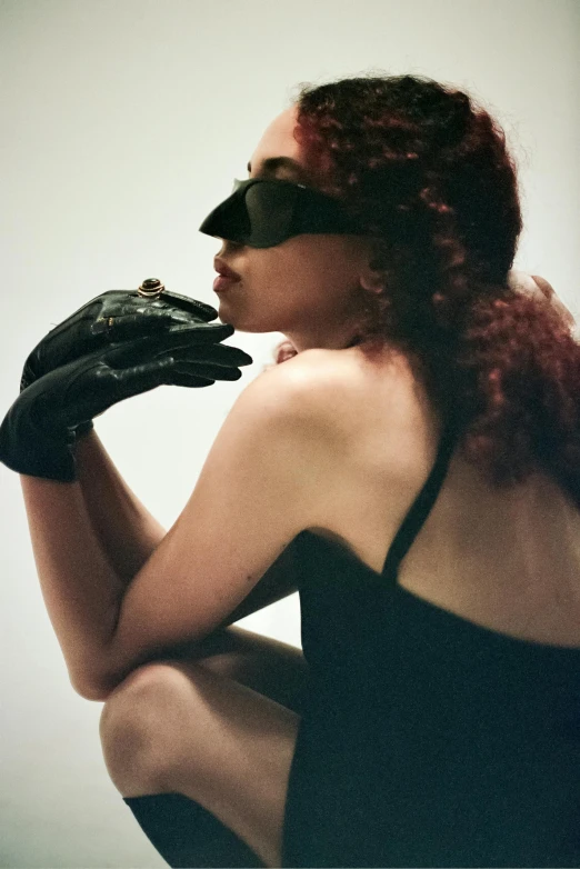 a woman in black leather gloves holding her face with one hand