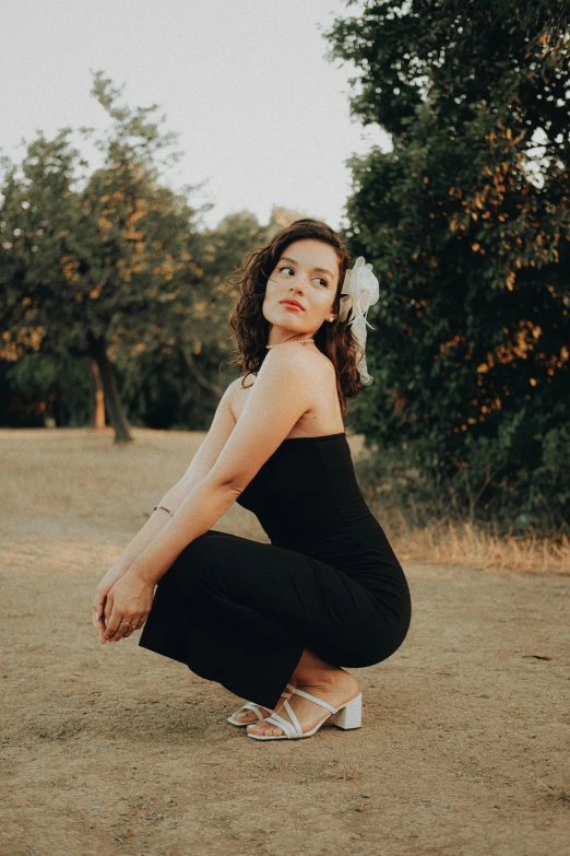 a woman in black dress kneeling on the ground