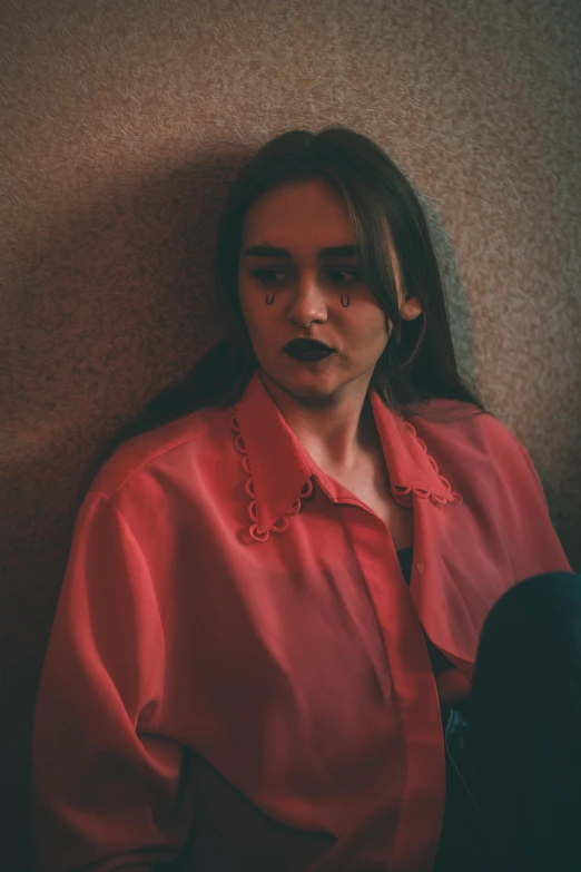 a young lady sitting against the wall in a room