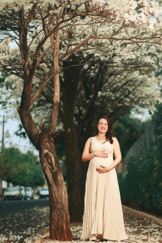 a woman posing by some trees in front of a tree