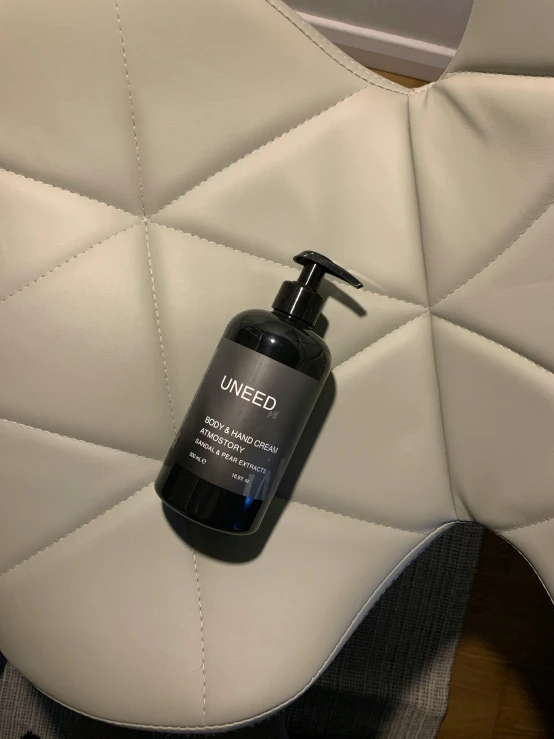 a bottle of lotion sitting on top of a white leather seat