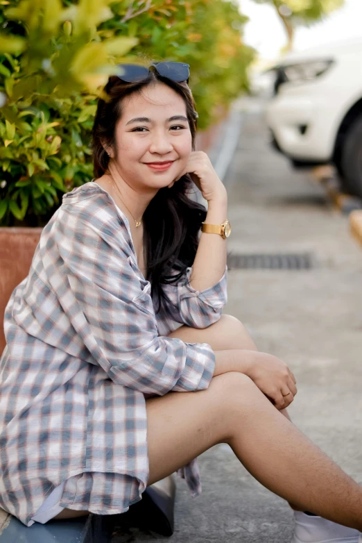 woman sitting down outside in a plaid shirt