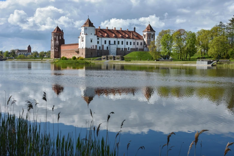 a white castle stands on the shore of a large body of water