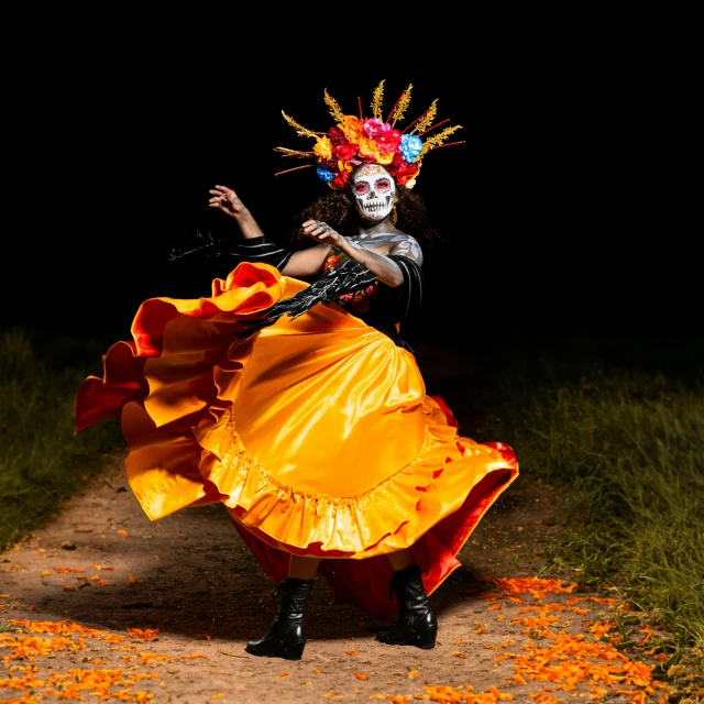 a mexican dancer poses in her orange skirt and mask