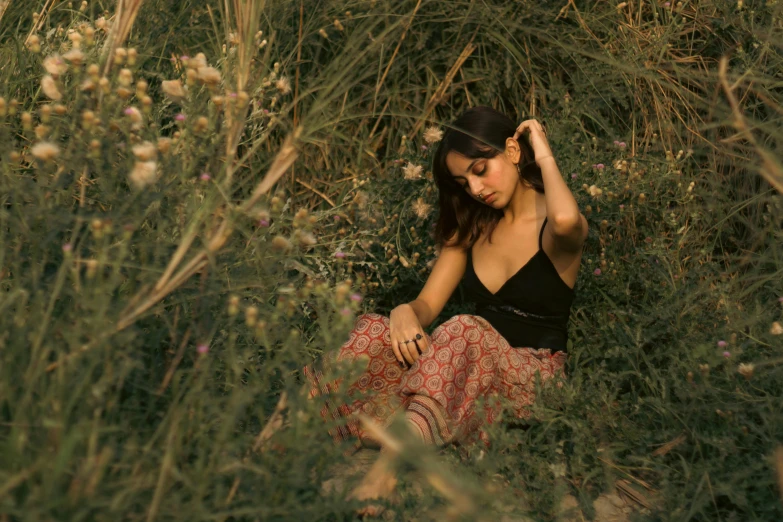 a woman in a dress sitting amongst plants