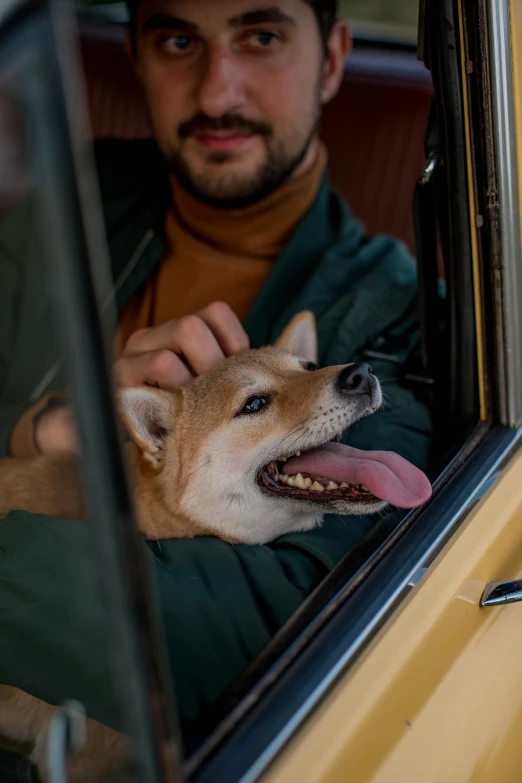 man holding a dog in a car with its mouth out