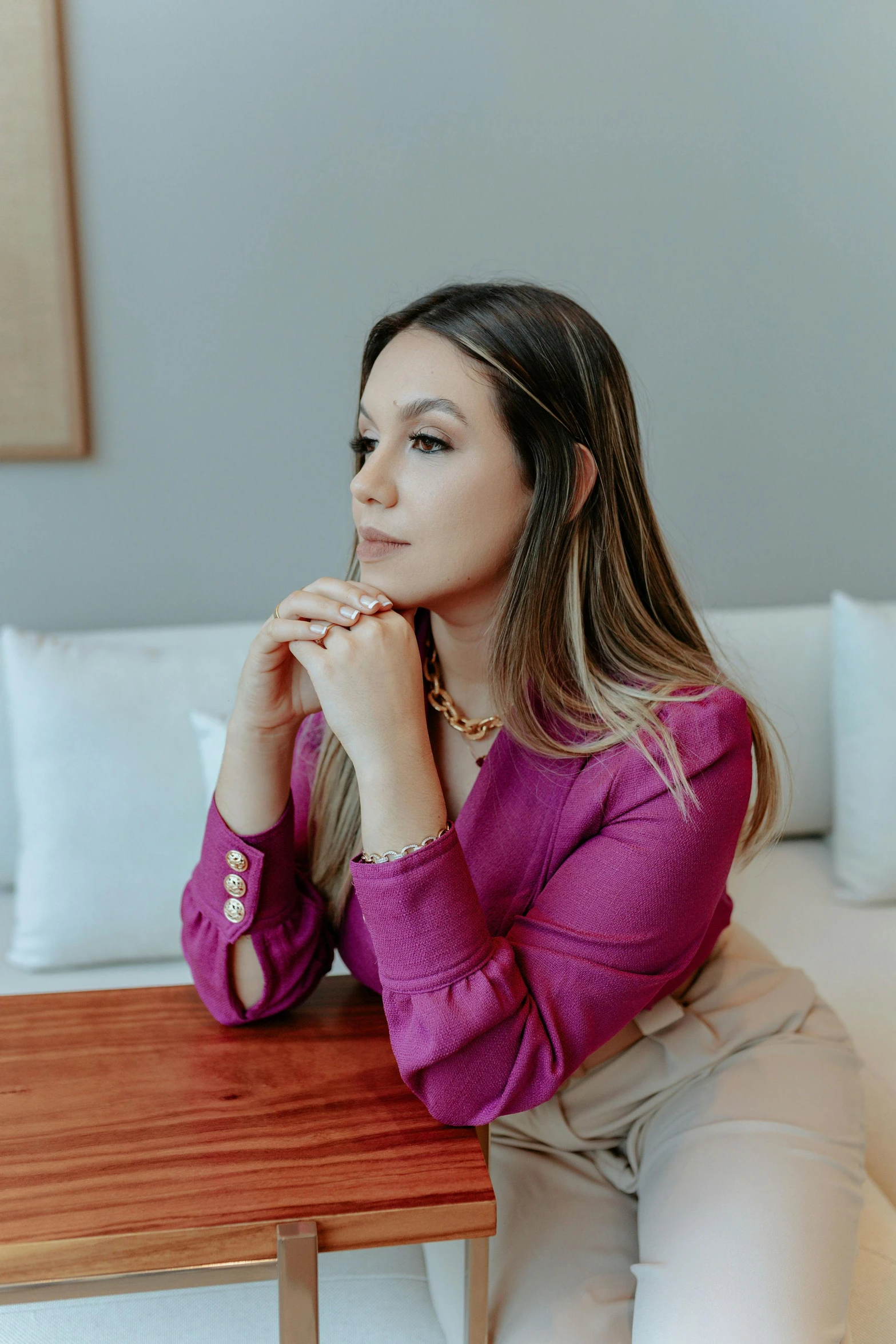 a woman sitting on a bed wearing a pink sweater